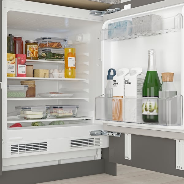 Réfrigérateur ouvert avec étagères réglables, contenant divers aliments et boissons, sous l’armoire.