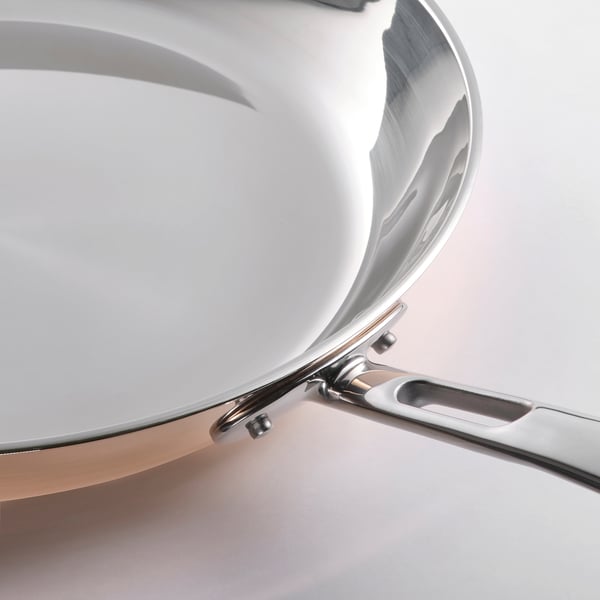 Poêle à frire en acier inoxydable de haute qualité avec une surface brillante et lisse et une poignée robuste, réfléchissant la lumière.