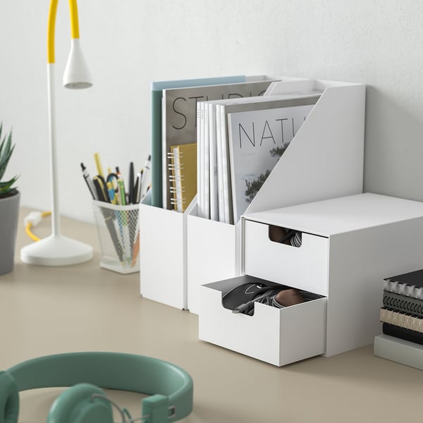 Un mini coffre FJÄDERHARV blanc sur un bureau, pour ranger des livres et des accessoires technologiques.
