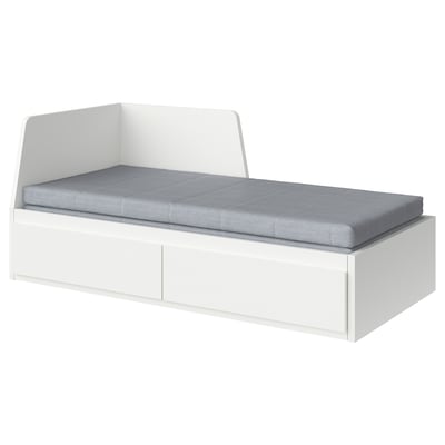 Un lit de repos blanc FLEKKE avec coussin gris, en panneaux de particules et mousse, conçu pour les petits espaces.