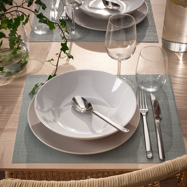 Mise en place de la table avec des sets de table, des assiettes et des couverts FLYGFISK, prêts à être dégustés.