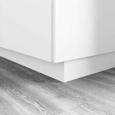 Base d’armoire de cuisine blanche avec socle, couvrant l’espace entre le sol et l’armoire.