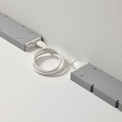 Deux appareils FÖRNIMMA rectangulaires gris reliés par un cordon blanc, utilisés pour relier et contrôler plusieurs lampes avec une seule alimentation secteur.