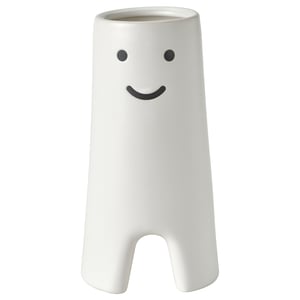 Vase en céramique blanche avec un design de visage souriant, de forme cylindrique avec de petites découpes à la base.