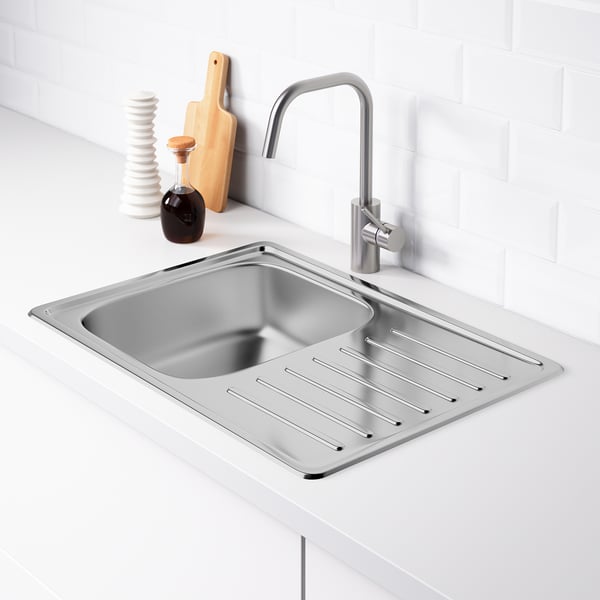 Évier de cuisine en acier inoxydable avec égouttoir et robinet réversibles, comptoir blanc, dosseret carrelé.