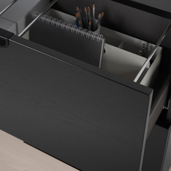 Tiroir de bureau noir ouvert, révélant des fournitures de bureau organisées, mettant en valeur un rangement sécurisé avec un mécanisme de verrouillage.