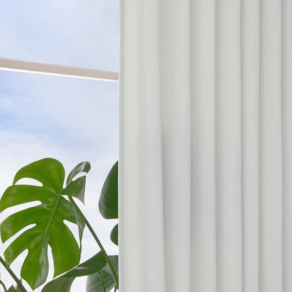 Rideaux blancs avec de grandes feuilles vertes, montrant des rideaux drapés lisses et un effet d’intimité.