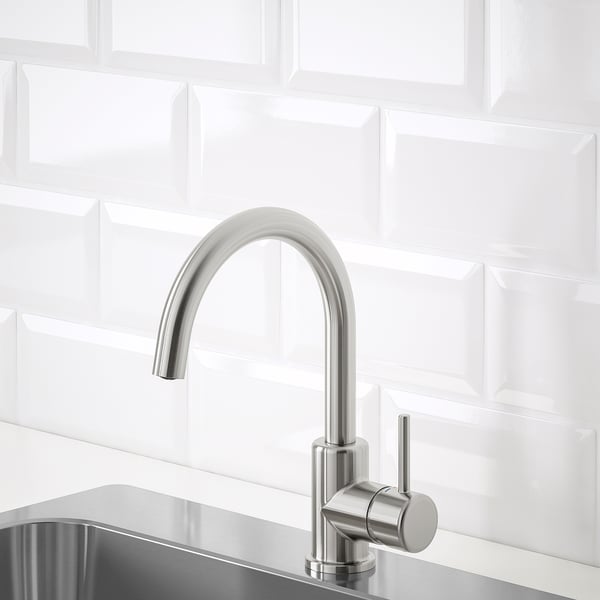 Robinet de cuisine moderne en acier inoxydable avec un design élégant et incurvé contre un dosseret en tuiles blanches, mettant l’accent sur l’efficacité de l’eau et la durabilité.