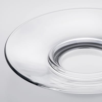Soucoupe en verre transparent sur une surface blanche, mettant en valeur son bord lisse et transparent et sa conception durable.