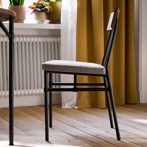 Chaise moderne avec assise rembourrée et dossier en bois, contre des rideaux jaunes et un plancher en bois.