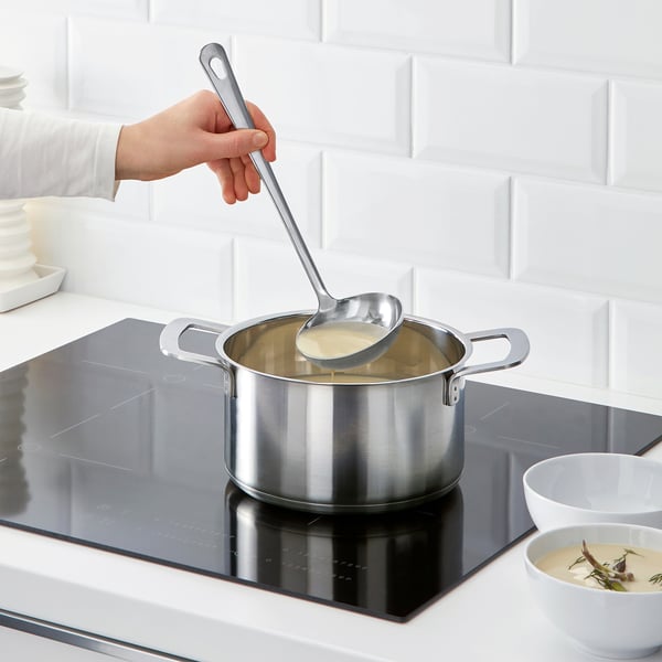 Verser une soupe crémeuse avec une louche GRUNKA sur une cuisinière à induction.