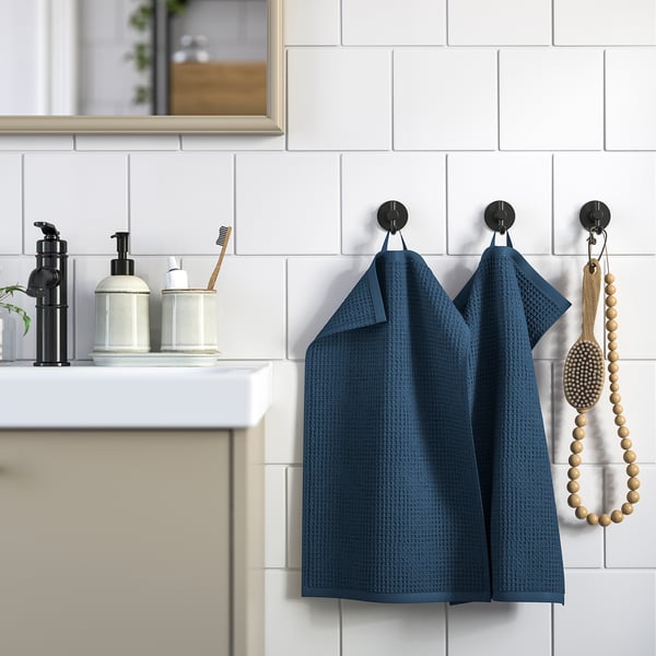 Des serviettes Blue GULLDYNA sont suspendues à des crochets muraux, avec des distributeurs et une cuillère en bois dans la salle de bain.