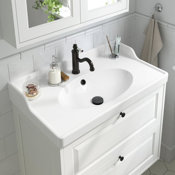 Lavabo de salle de bain blanc avec robinet et levier noirs, aérateur, distributeur de savon, porte-brosse à dents.