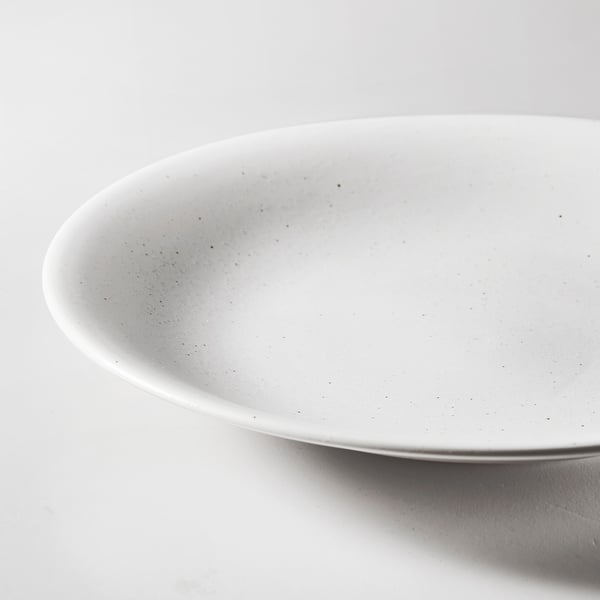 Gros plan des assiettes HARMYNTA surface lisse et texturée blanche, mettant en valeur sa finition en porcelaine durable et de haute qualité.