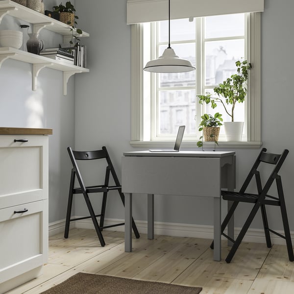 Bureau à domicile compact avec table HAUGA, deux chaises, des étagères et une grande fenêtre.