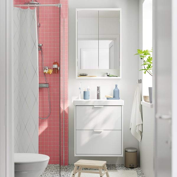 Petite salle de bains moderne avec carrelage rose, armoires HAVBÄCK blanches et sol gris.