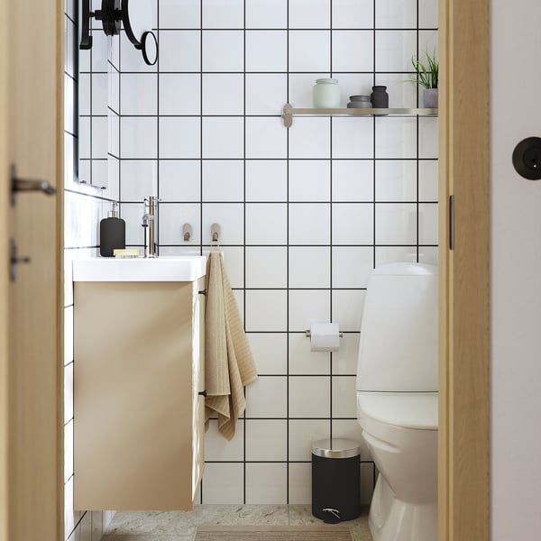 Une salle de bain moderne avec un mur carrelé blanc, des accents noirs et une serviette beige. Design minimaliste aux lignes épurées et aux couleurs contrastantes.