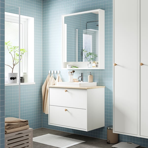 Meuble de salle de bain HAVBÄCK murale avec plan de travail en bambou, miroir et murs carrelés bleus. Design épuré et minimaliste avec un lavabo en céramique.