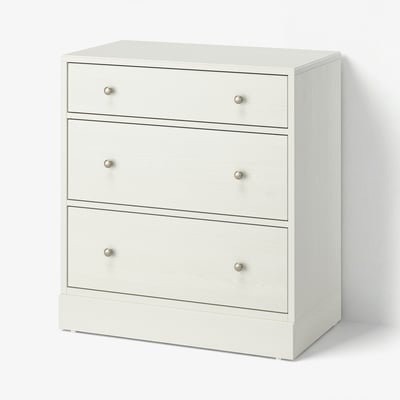 Une commode blanche HAVSTA avec trois tiroirs, en pin massif et en carton de fibre, présentant un design simple et fonctionnel.