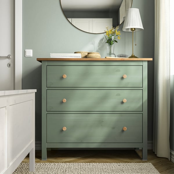 Commode HEMNES verte avec 3 tiroirs, plateau en bois, poignées en laiton, lampe de table, miroir.