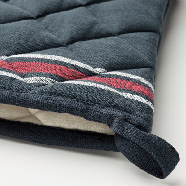 Un gros plan d’un coin de coussin à rayures bleu foncé et rouge, noué avec un tissu bleu foncé, mettant en valeur des matériaux de haute qualité et un savoir-faire.