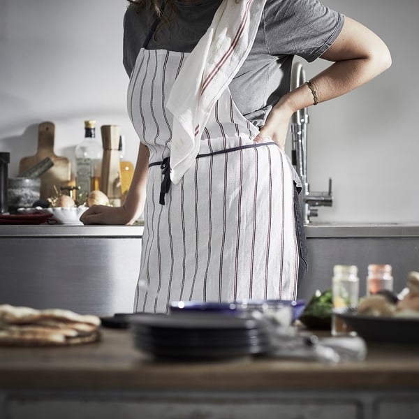 Personne dans la cuisine avec tablier rayé, comptoir avec des articles.