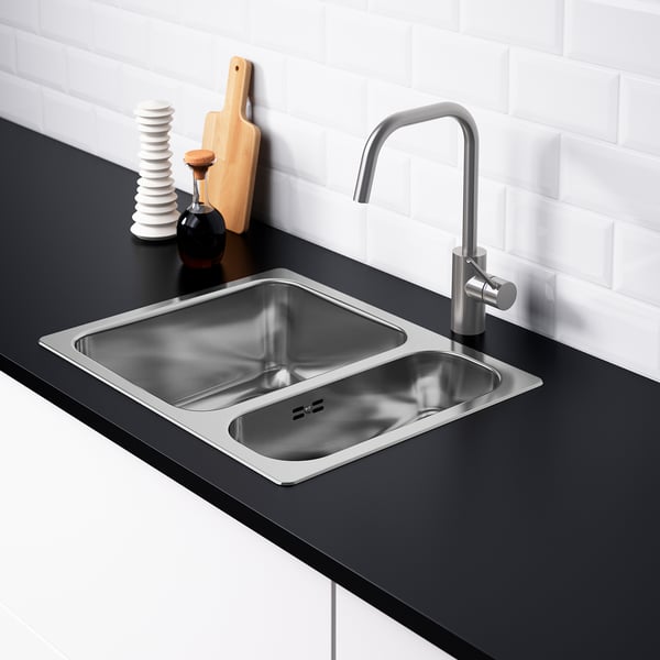Évier moderne à double vasque avec robinet, comptoir noir, dosseret blanc et piège à eau.