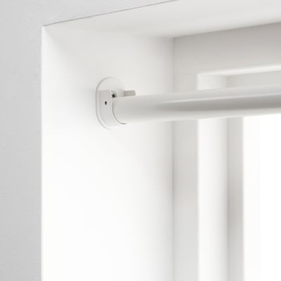 Gros plan d’un support blanc monté en hauteur sur un mur, conçu pour maintenir solidement les tringles à rideaux entre les murs opposés.