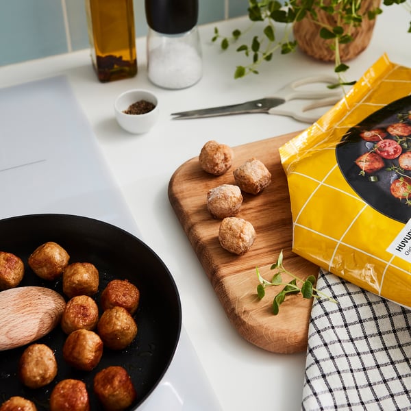 Boulettes de viande crues et cuites, assaisonnement HUVUDROLL, herbes sur le comptoir.