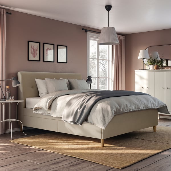 Lit de rangement beige IDANÄS avec tête de lit, draps gris, tiroirs à fermeture douce, tables d’appoint et lampes, rideaux, œuvres d’art, armoire.