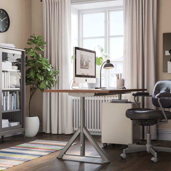 Bureau à domicile avec bureau IDÅSEN, chaise et grande fenêtre avec rideaux et tapis.
