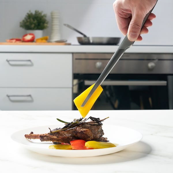 À l’aide d’une pince à épiler, on enlève les herbes de la viande sur l’assiette.