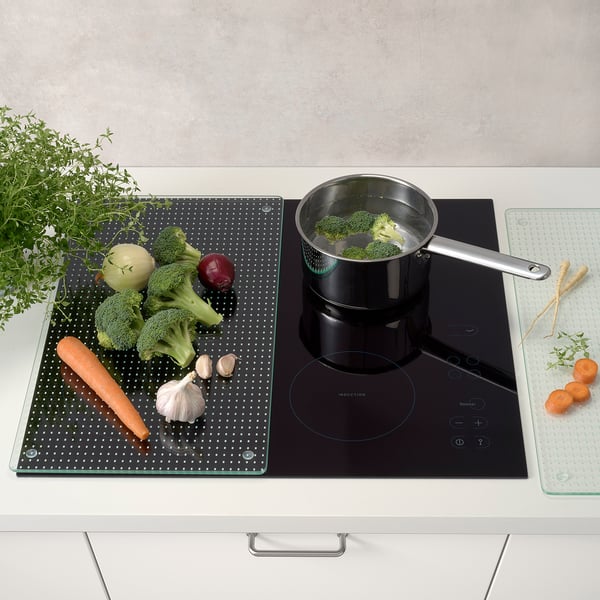 Du brocoli mijote, des légumes sur tapis, des herbes à proximité.