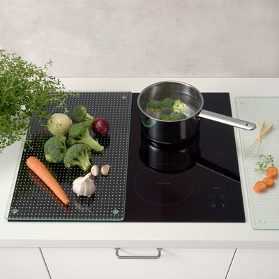 Du brocoli mijote, des légumes sur tapis, des herbes à proximité.