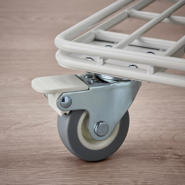 Gros plan d’une roue de chariot. Montre une roulette lisse et durable avec frein, fixée à un cadre robuste et propre, reposant sur un plancher en bois.