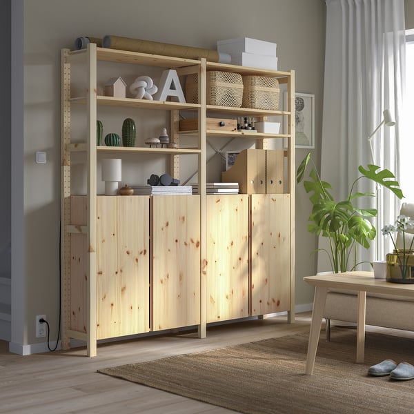 Unité de rangement IVAR en bois clair avec étagères et armoires, exposant la décoration et les livres dans une pièce minimaliste.