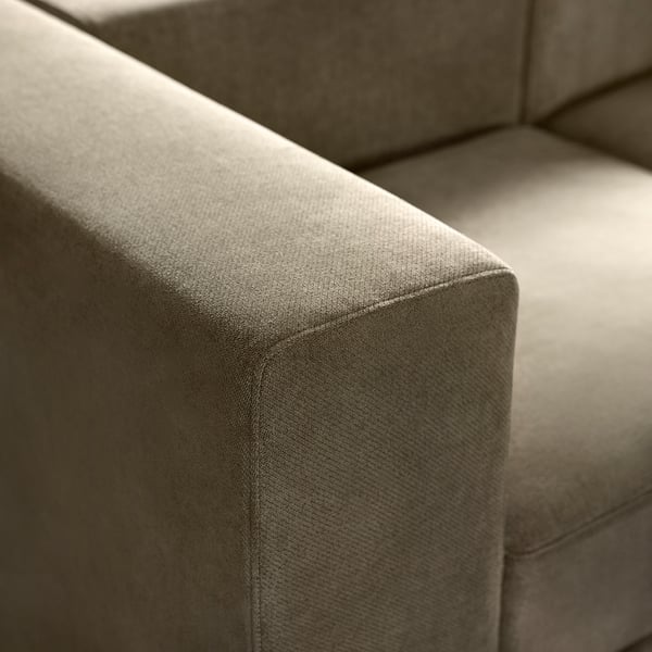 Gros plan d’une section d’un canapé moderne gris recouvert de tissu. Des lignes douces et épurées et des coussins profonds suggèrent confort et qualité.
