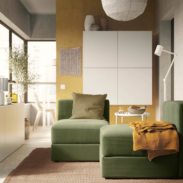 Salon moderne avec canapé JÄTTEBO texturé vert, coussin moelleux, décor en bois et mur jaune.