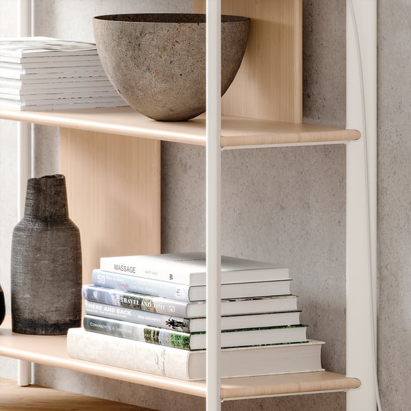 Bibliothèque moderne avec étagères en bois clair, cadre en métal blanc, bols et livres.