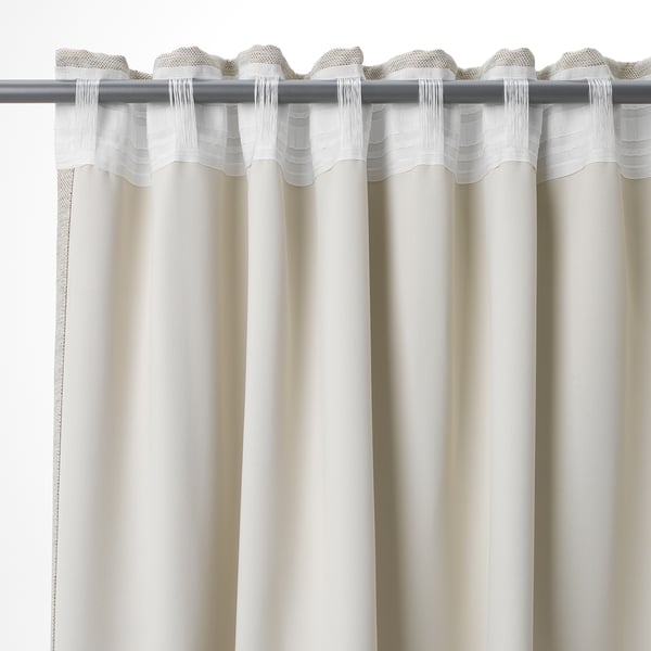 Les rideaux blancs pendent avec des plis, offrant de l’intimité et assombrissant la pièce. Languettes et crochets visibles en haut.