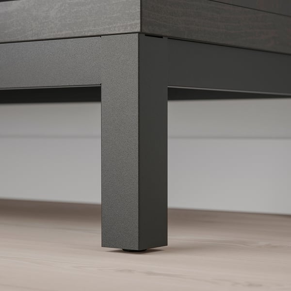 Pied de table moderne en métal avec finition texturée, supportant une surface élégante sur un plancher en bois.