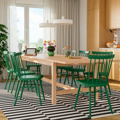 Salle à manger moderne avec table KARSKÄR, chaises et grandes fenêtres. Vase centré, verres et cruche. Style scandinave.