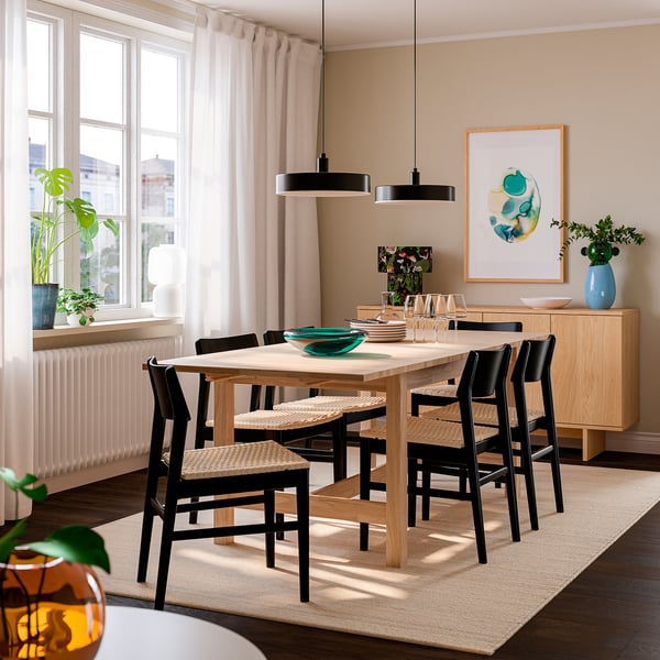 Table à manger extensible avec 6 chaises, sièges tissés, art abstrait au-dessus.