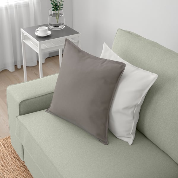 Un canapé vert avec des coussins gris et blancs, mettant en valeur son design confortable et accueillant.