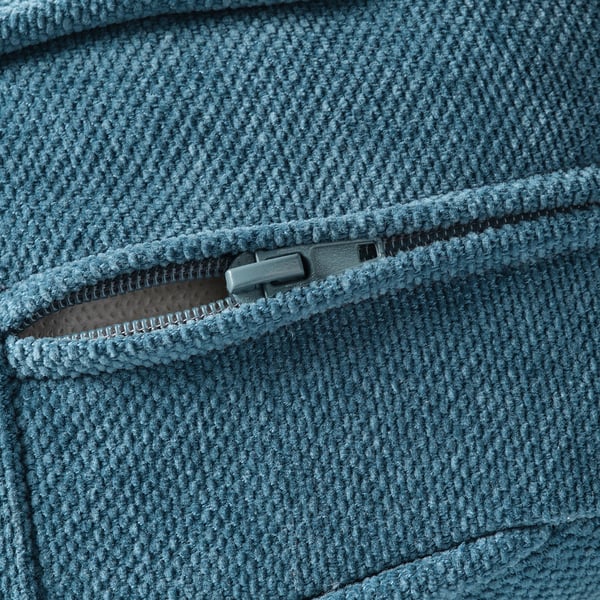 Gros plan d’un tissu bleu doux et texturé avec une fermeture éclair robuste, mettant en valeur un matériau de qualité.