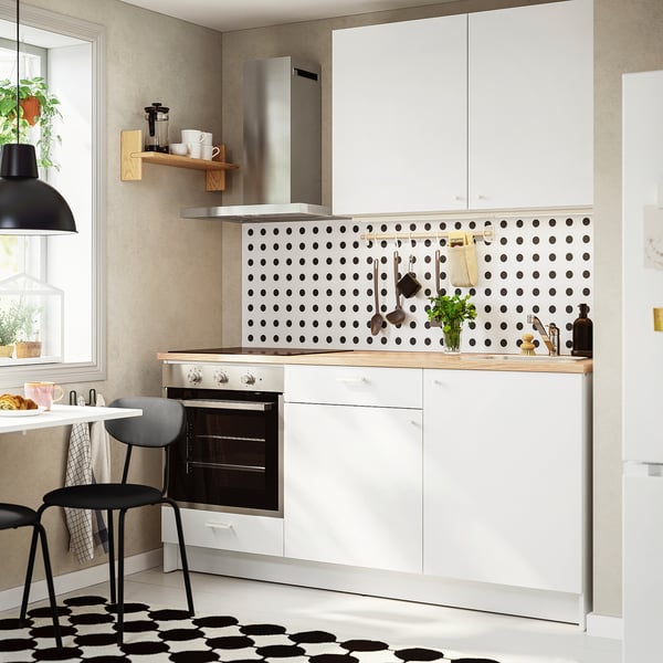 Configuration de cuisine blanche moderne. Dosseret à pois noirs, étagère en bois, petit four, accessoires de comptoir. La conception compacte s’adapte bien aux petites cuisines.
