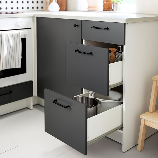 Armoire de cuisine moderne avec trois tiroirs ouverts, montrant le rangement des ustensiles. Gris et blanc avec poignées noires, conçu pour une utilisation pratique dans l’espace.