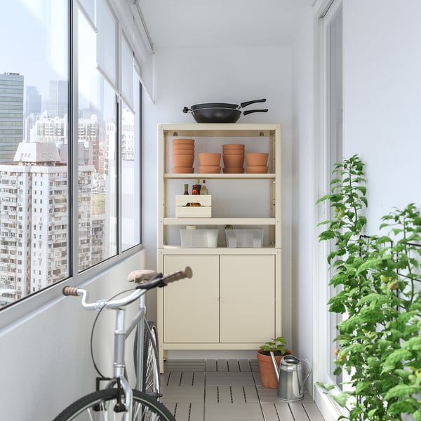 KOLBJÖRN : meuble de rangement blanc avec étagères et armoire en acier. Tient des pots de fleurs et un vélo sur le balcon.