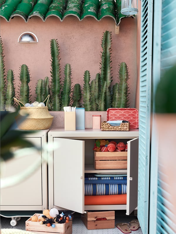 Armoire blanche KOLBJÖRN avec cactus, paniers et outils sur le balcon.