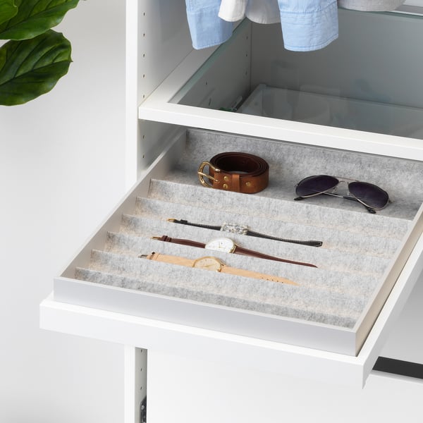 Un organisateur de tiroir blanc ouvert avec plusieurs compartiments contenant des montres, une ceinture et des lunettes de soleil.
